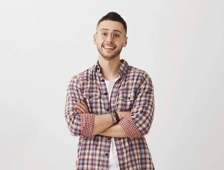 Caucasian macho man standing with crossed hands and smiling with lifted eyebrows, listening to someone but doubting words, standing over gray background